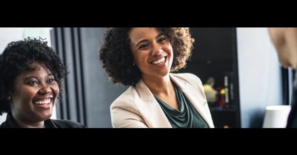 Two women smiling while looking towards the side