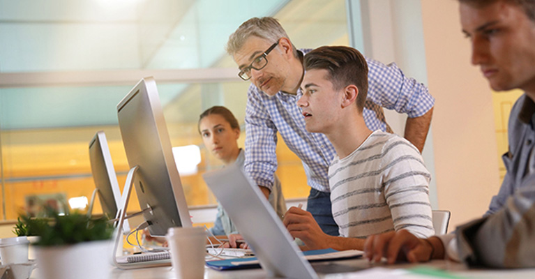 Teacher helping students in a computer studio