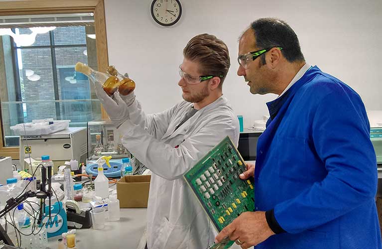 Two males conducting an experiment and examining materials.