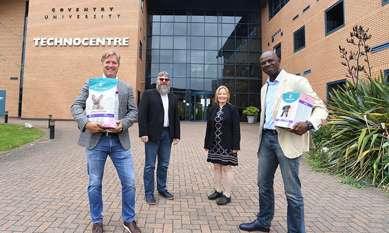 Percuro Primal Pet Food Ltd team standing outside Coventry University building holding their products.