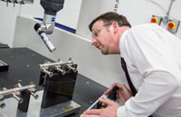 Lecturer taking a close look at a microscope on a desk