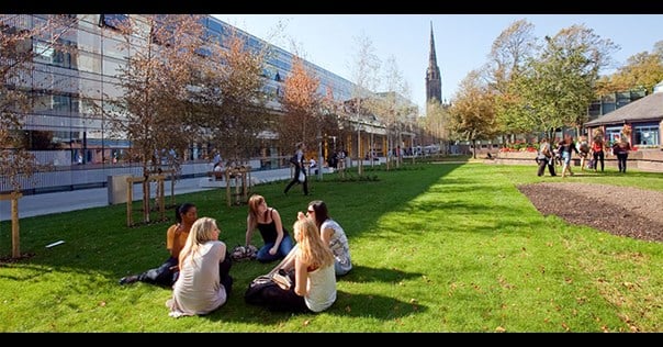 Students sitting on the grass outside a Coventry University building