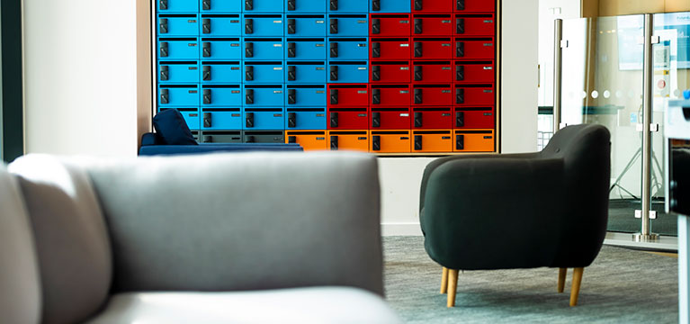 Grey sofa and chair next to a wall of multi coloured lockers