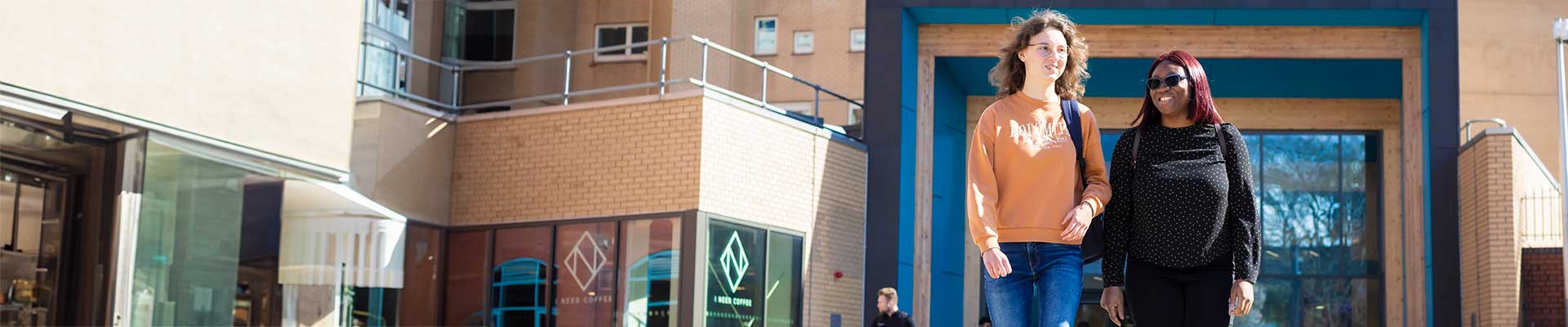 Students walking on campus with the library building behind