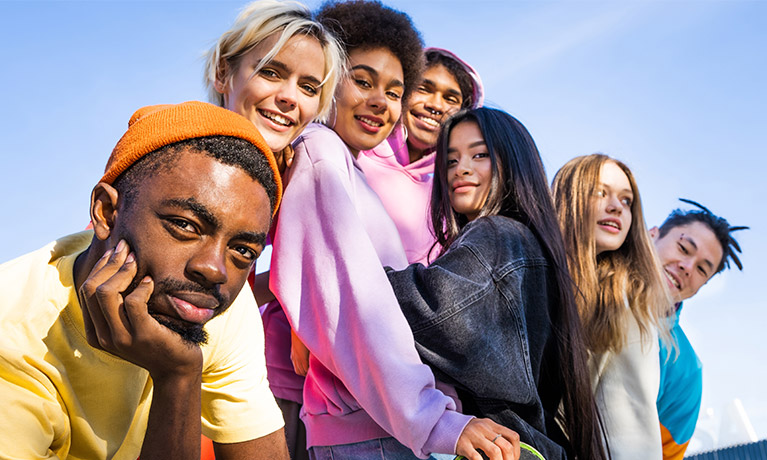 A grouo of students smiling at the camera against a blue sky in the background.