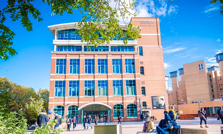 University building surrounded by young students walking outdoors on a sunny day