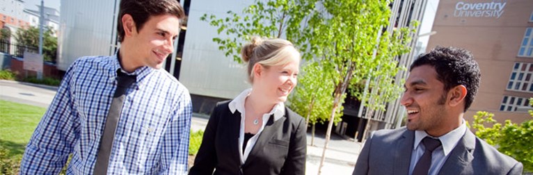 Three graduates walking across campus