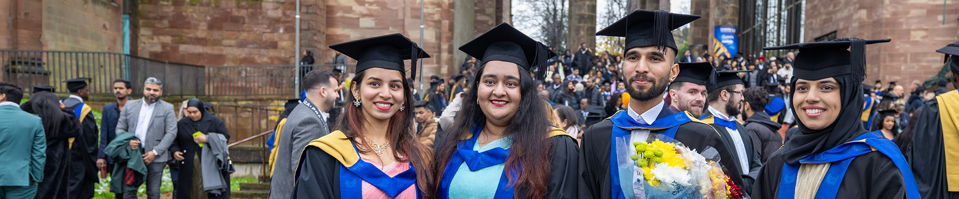 Group of graduates in their gowns standing in university square