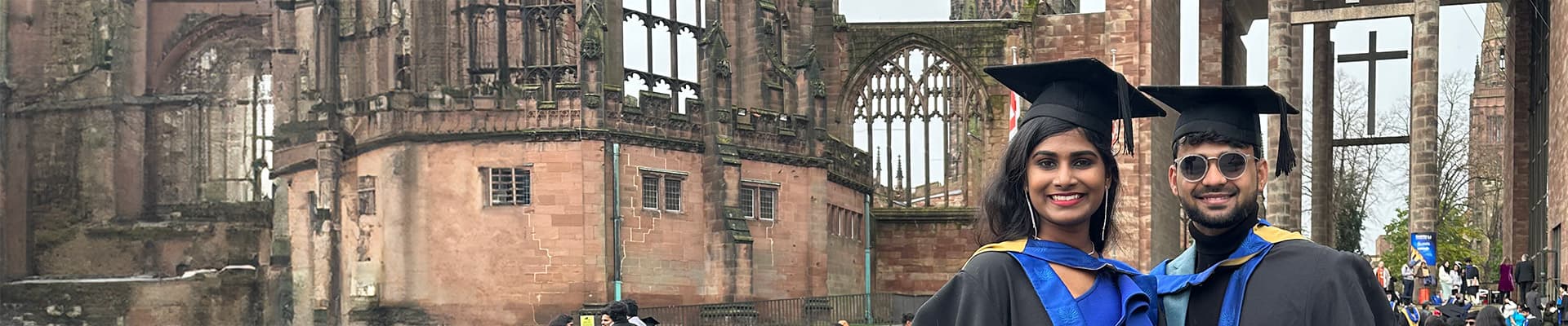 Two graduates stood in the Cathedral ruins
