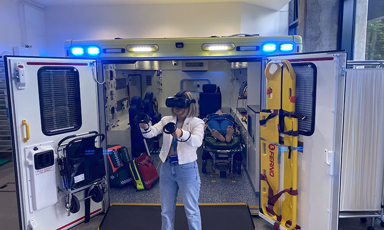 A woman wearing a VR headset stood in front of an ambulance