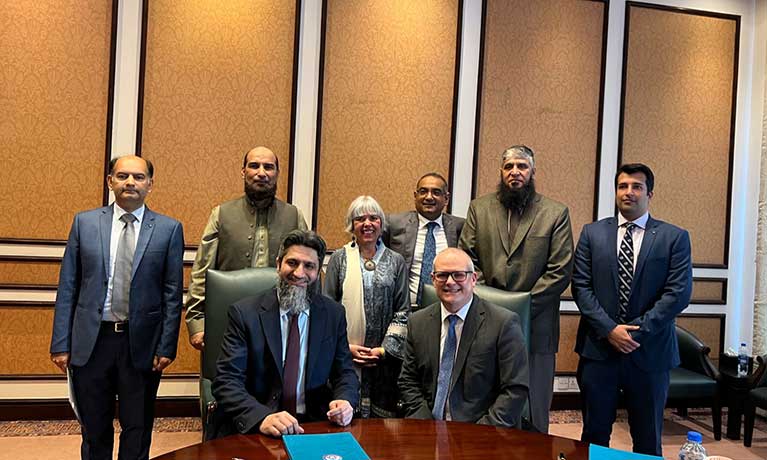 Group of Coventry University and Pakistani educational institute leaders gathered round table signing document