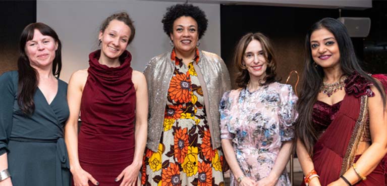 Five women standing next to one another smiling