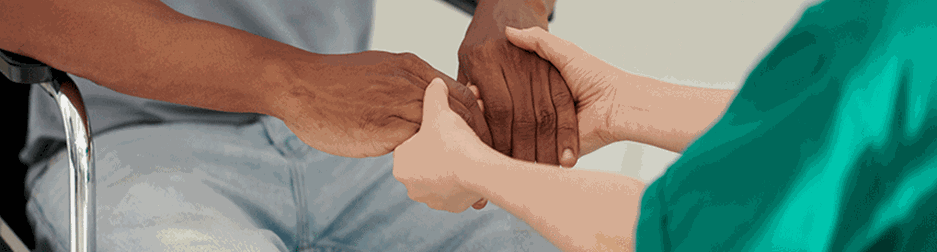 Caregiver holding hands of person sitting in wheelchair to show support and care