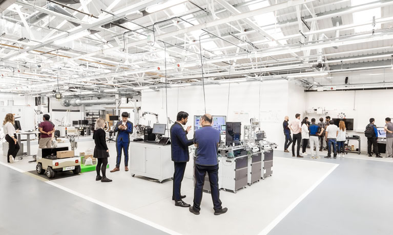 Group of academics and researchers in manufacturing building at different stations