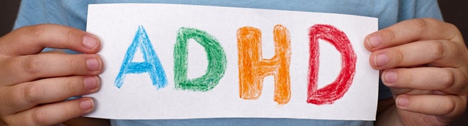 person holding a sign with adhd written in different colours
