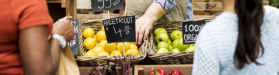 Greengrocer at a farmers market selling fresh fruit and vegetables