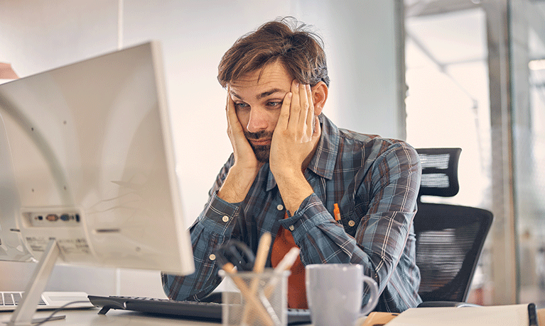 Exhausted male worker using computer in office