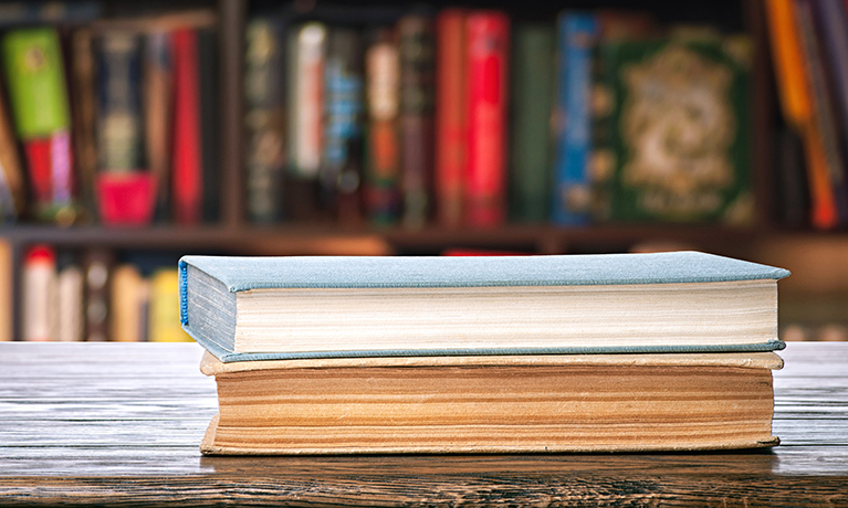 Two books stacked on top of one another on a desk