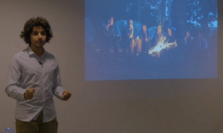 A young man stands in front of a projected image. 