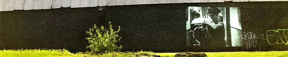 an image of a man projected onto the side of a block of flats