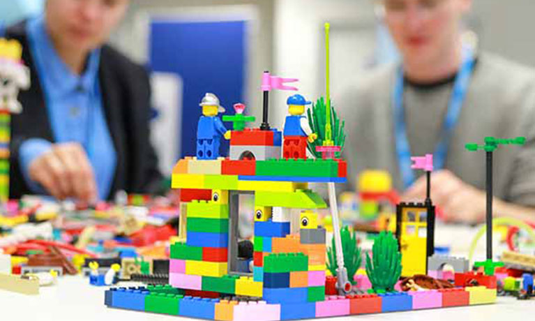 two people sit behind a large lego construction