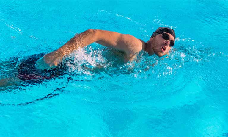 Man wearing swimming cap doing front crawl in swimming pool