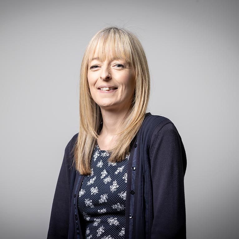 Lorna Everall smiling against a grey background.