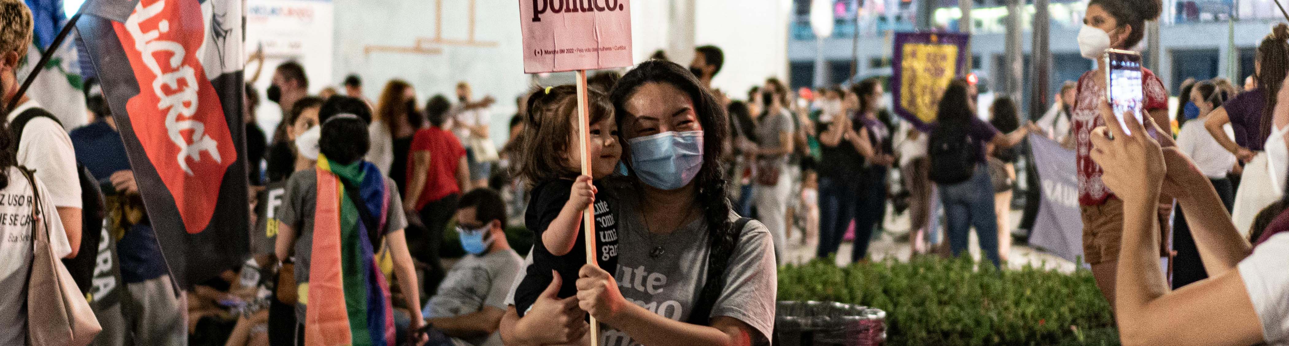 Image of a mother holding her child amongst a protest