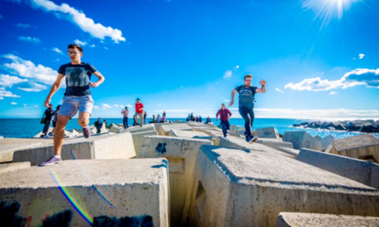 Students walking on rocks near the sea