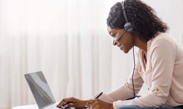 women working  on a laptop wearing a headset