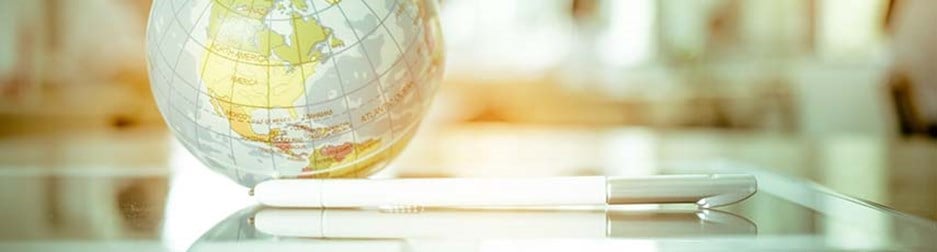 Globe on a glass table with tablet and pencil