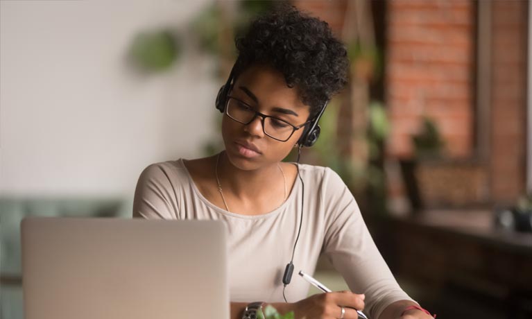 Girl reading from laptop with headphones on