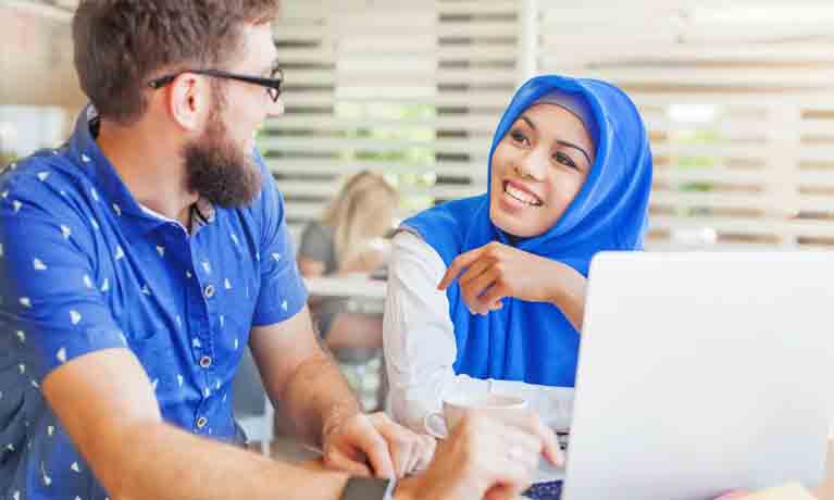 Two students working at laptop