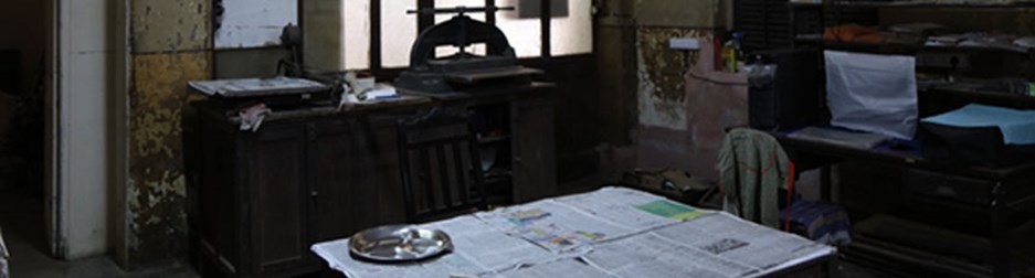 dark room with objects lying around and newspapers scattered around the table