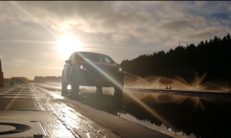 Car driving on a wet road with the sun shining down