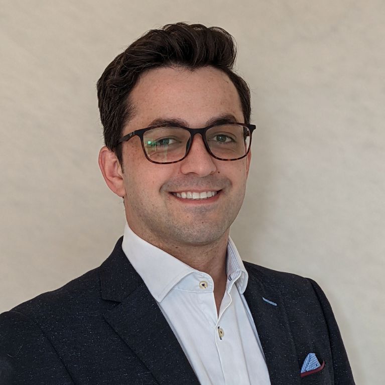 Picture of Marcos Kauffman smiling. Wearing glasses and a suit 