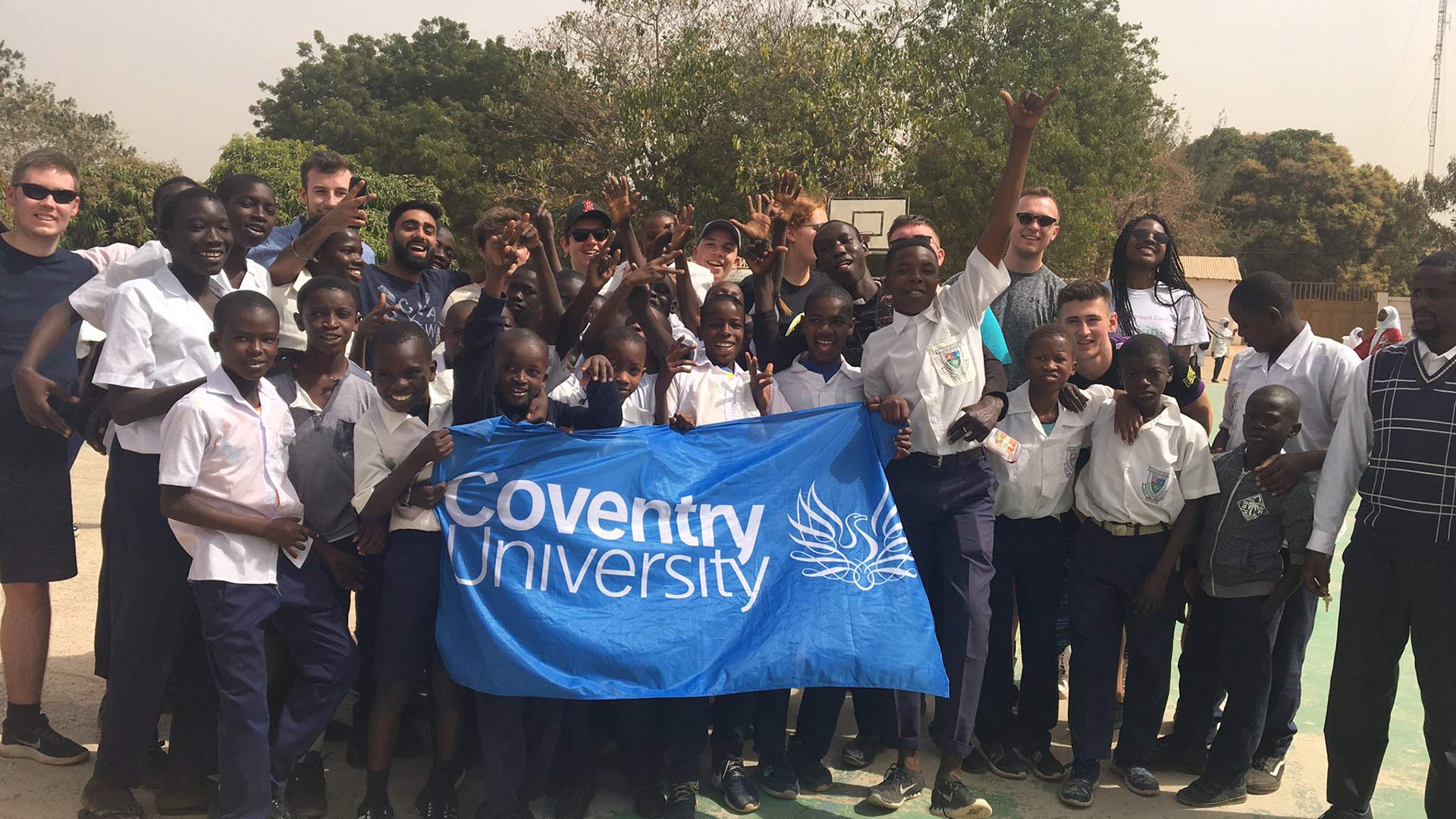 Community group and Coventry University students holding Coventry University flag