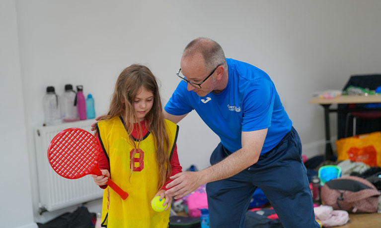 Professor Michael Duncan teaching a child to play tennis