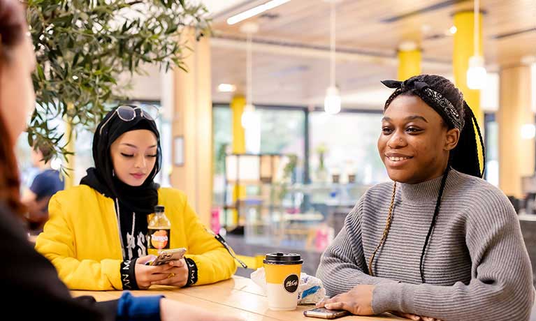 students sitting at a table in the Student hub