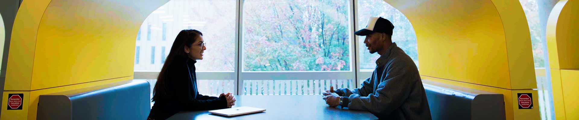 Student and success coach sitting in a booth in the the Student hub