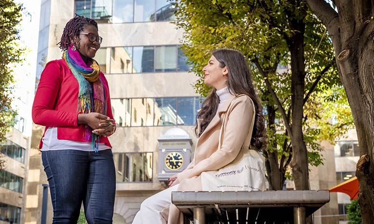 Female student standing outside campus on summers day.