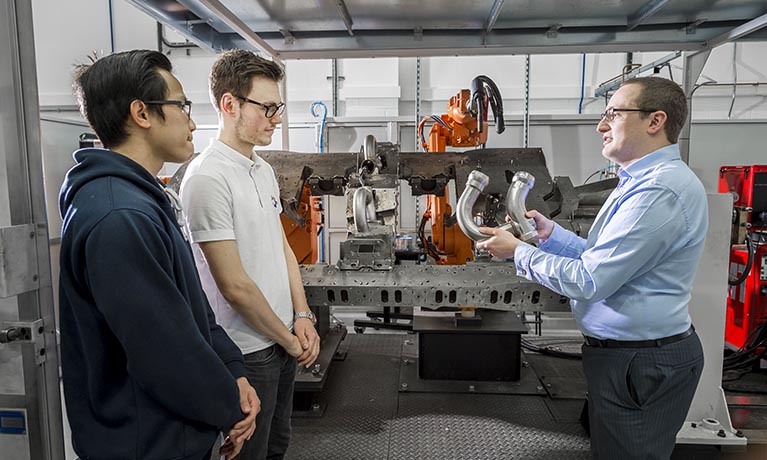 Two male students learning on engineering course with lecturer