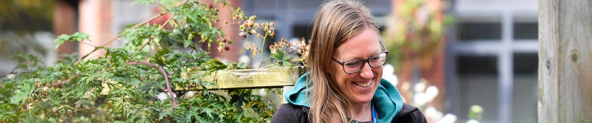 A female member of staff sat in the edible gardens with a laptop and a mug.
