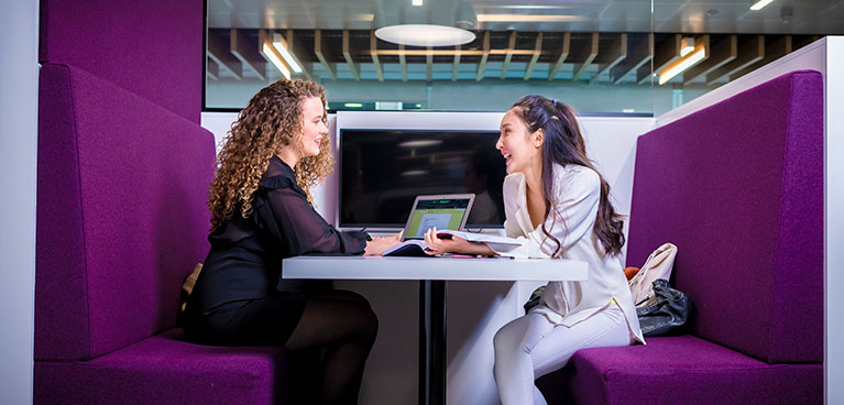 two students sitting and talking in a booth