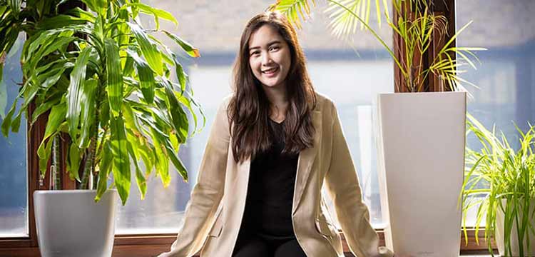Women posing for a photo sitting in between office plants