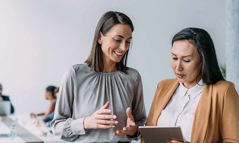 Two smartly dressed females looking at a tablet 