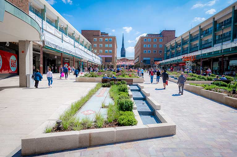 People walking through coventry city centre on a sunny day