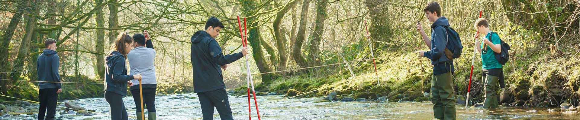 Group of students stood in shallow water measuring the flow
