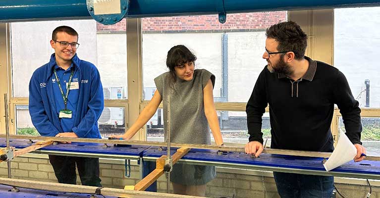Matthew Hoult standing with two lecturers looking over a water tank