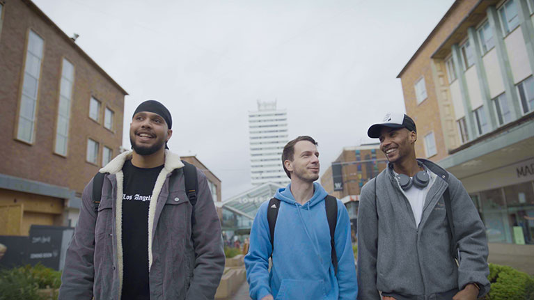 Group of male students walking through Coventry city centre on a grey day